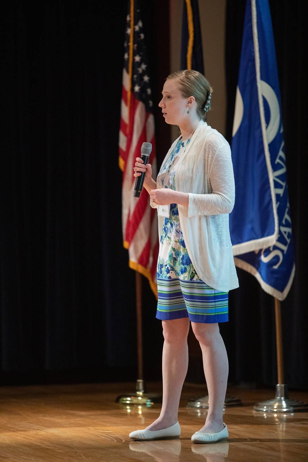 Student standing on stage, speaking to the audience